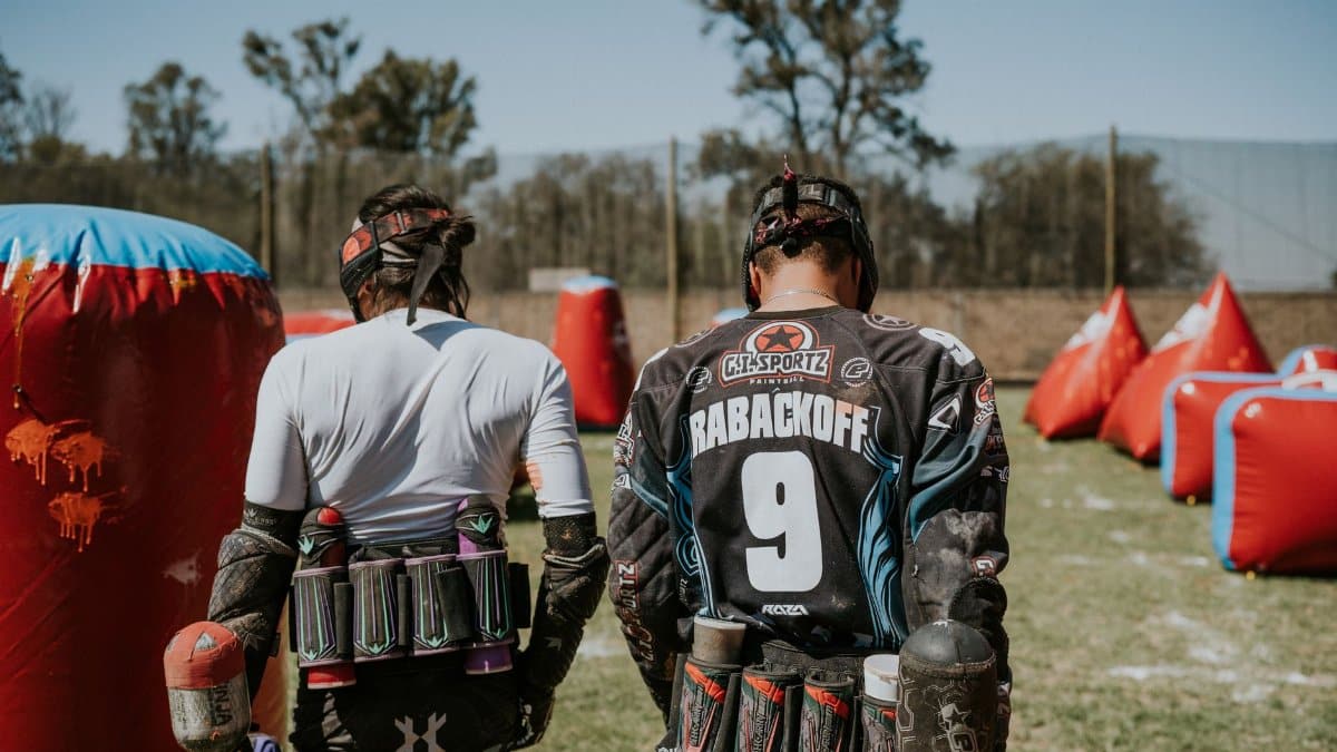 Two players in action on a paintball field, equipped and ready for the game.