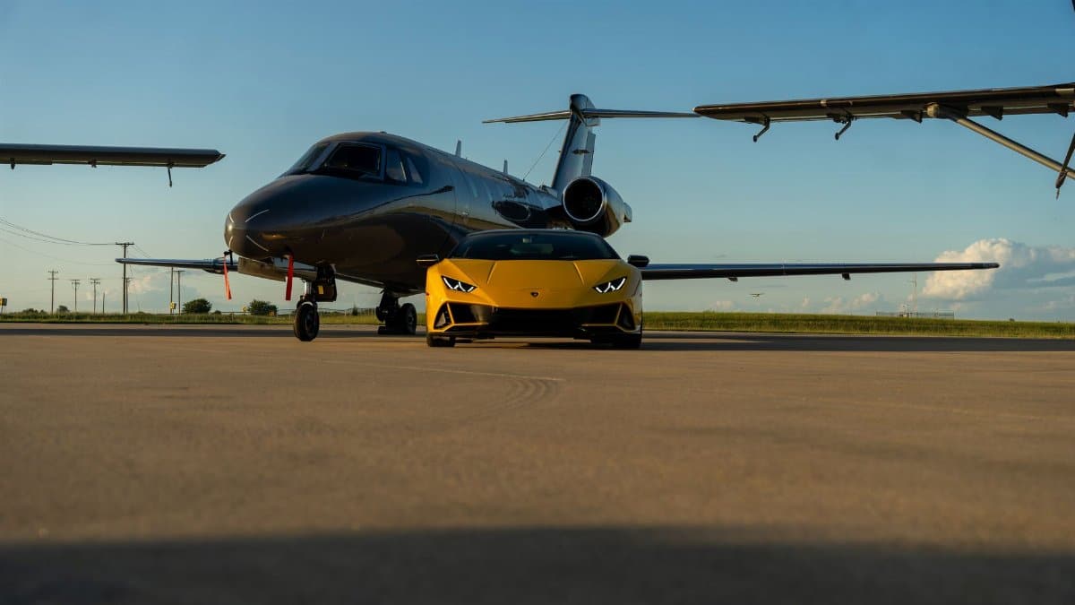 A sleek yellow sports car parked in front of a private jet on an airport tarmac in Illinois.