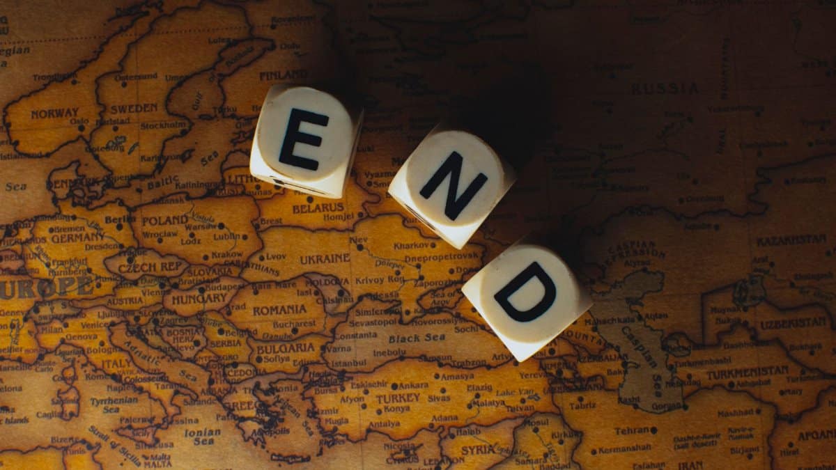 Close-up of dice spelling 'END' placed on a map of Europe, symbolizing finish line or travel completion.