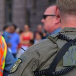 Police officers maintaining security at a public event with a crowd in the background.
