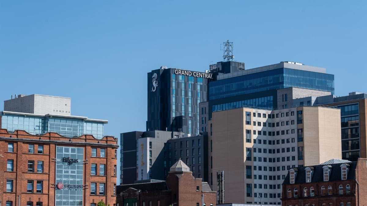 A daylight view of Belfast's urban skyline highlighting the Grand Central Hotel against a clear blue sky.
