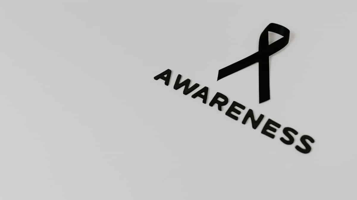 Minimalist image of a black ribbon symbolizing awareness against white background.
