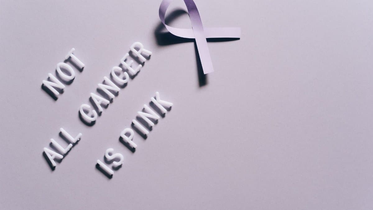 Cancer awareness poster with a purple ribbon on a gray background.