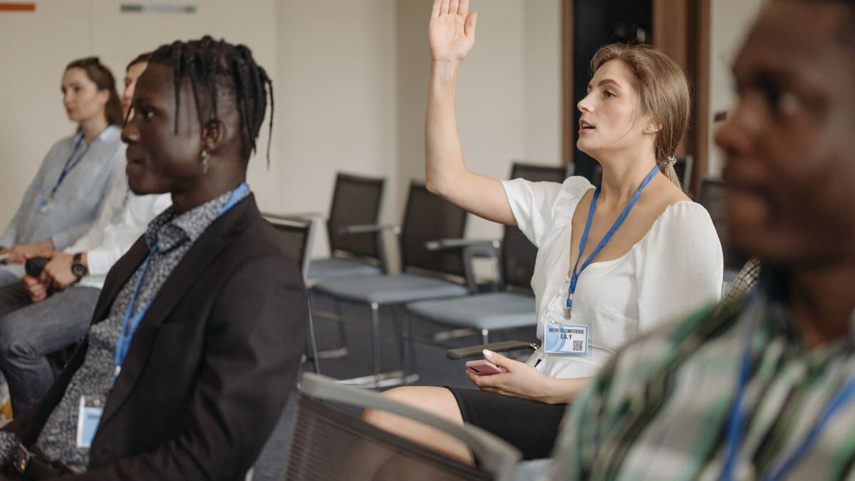 Adult woman raising hand during a business conference, showcasing engagement.