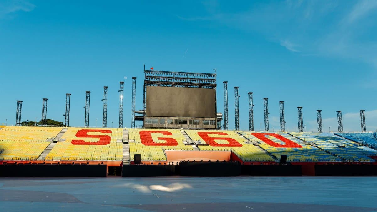 A vibrant empty stadium with colored seats and a clear blue sky, ideal for sports event posters.