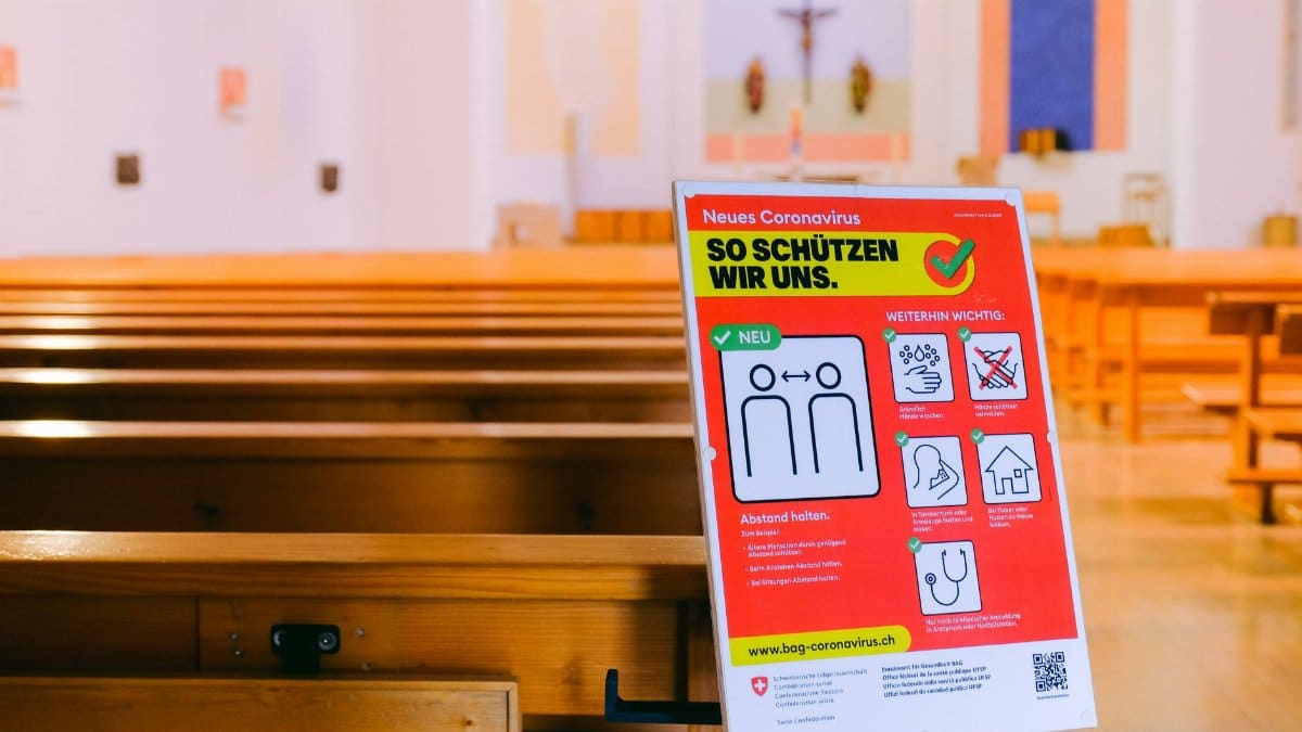 An empty church with Covid-19 safety sign emphasizing social distancing during pandemic.