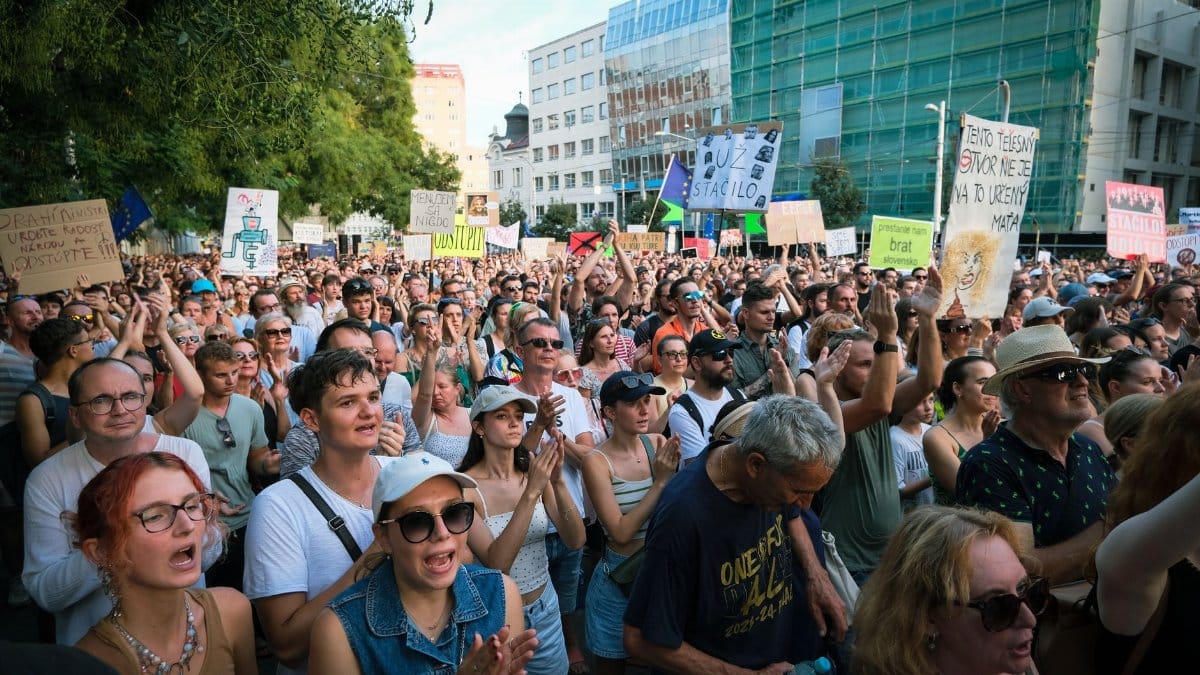 A large group of people in Bratislava peacefully protesting with signs in a city environment.