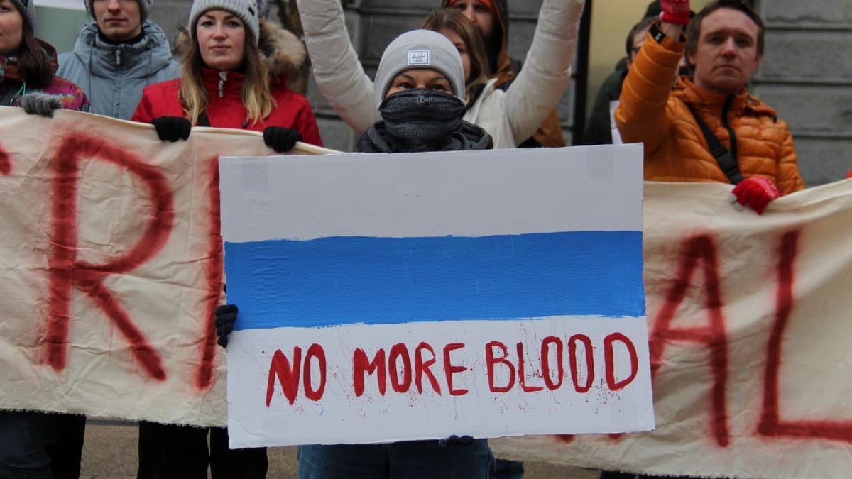 People protesting in Vancouver, holding a No More Blood sign against violence.
