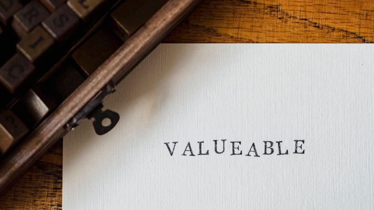 A classic typewriter typing 'VALUEABLE' on a white sheet on a wooden table.