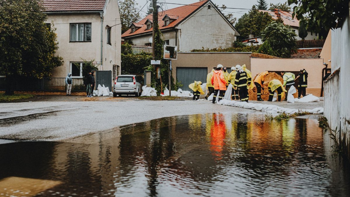 Emergency responders in reflective gear addressing floodwaters on a residential street.