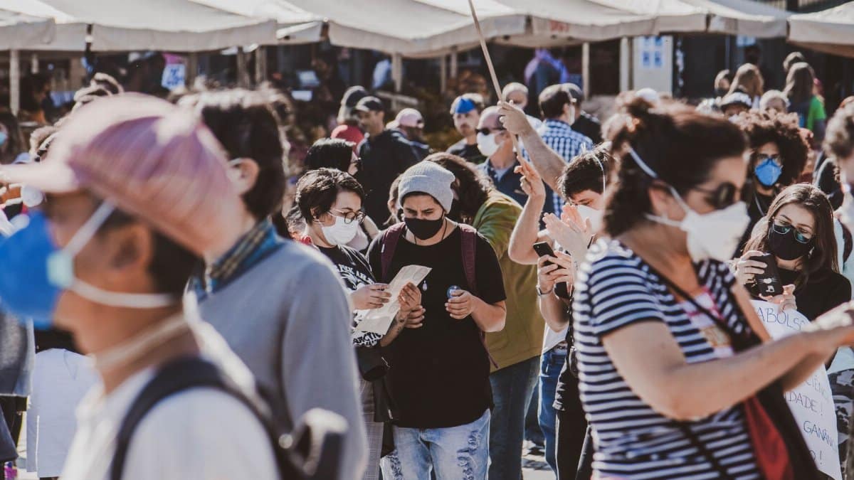 A diverse group of people wearing masks in an outdoor urban setting, highlighting community and safety.