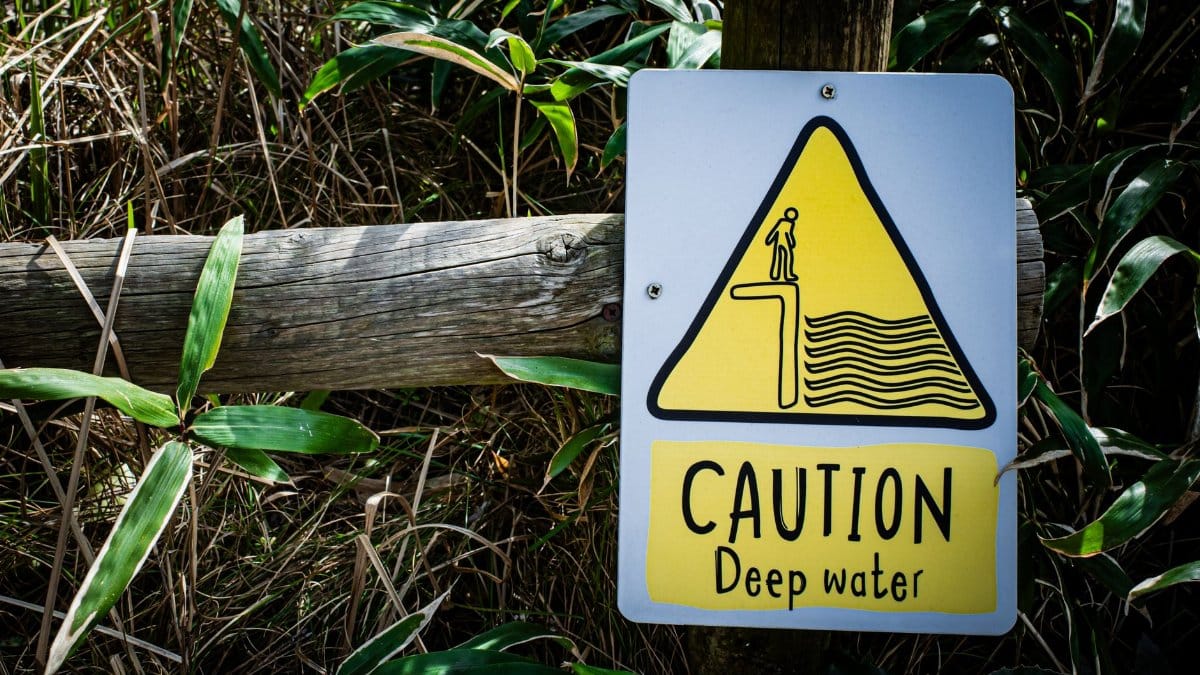 Caution deep water warning sign with a natural background, emphasizing safety near water bodies.