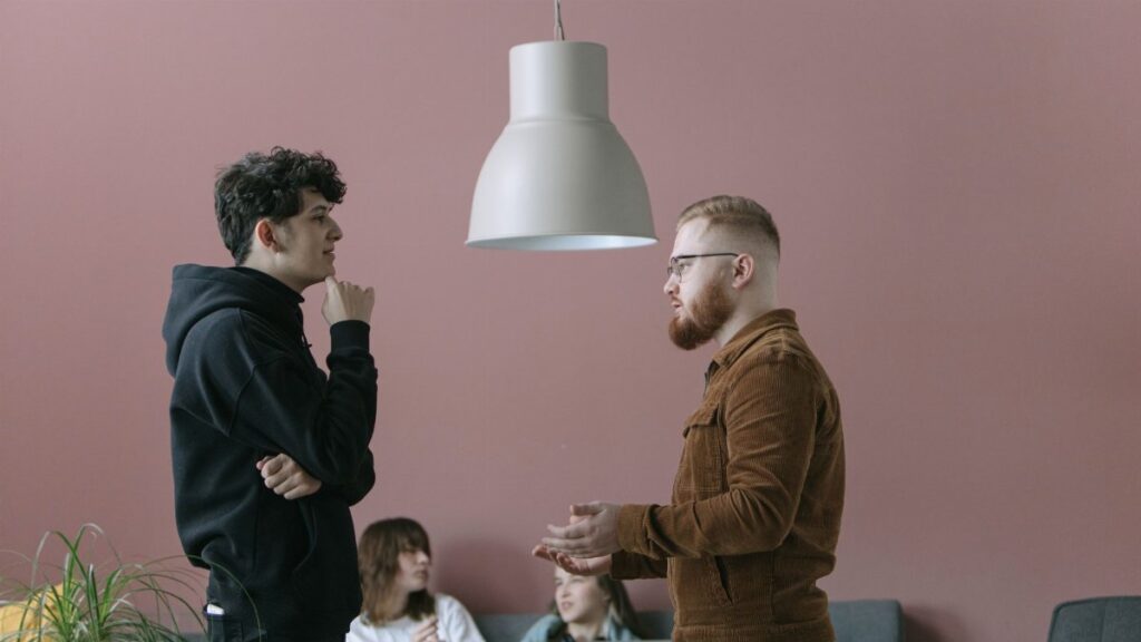 A group of young professionals engaging in a casual office meeting with a modern and stylish backdrop.