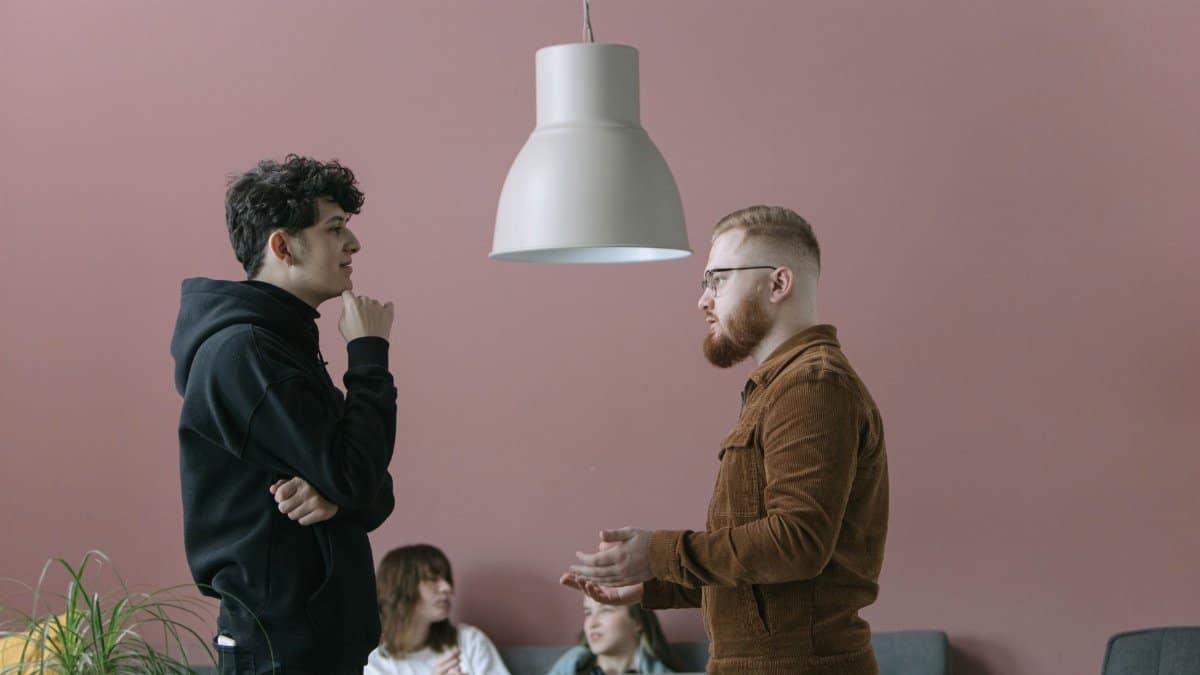 A group of young professionals engaging in a casual office meeting with a modern and stylish backdrop.