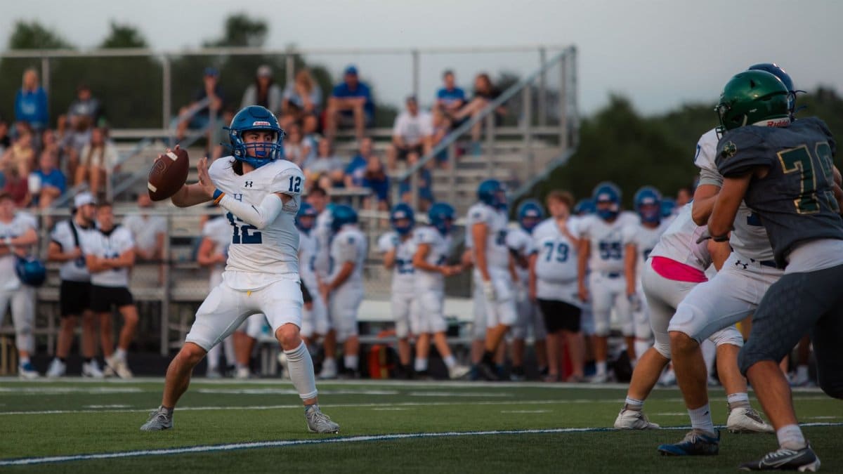 High school quarterback preparing to pass during an outdoor football game.
