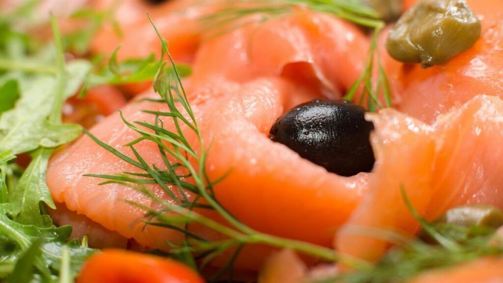 Delicious smoked salmon salad with olives, capers, and fresh dill leaves, perfect for a gourmet dish.