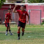Teen soccer player celebrates on the field during an outdoor match game.