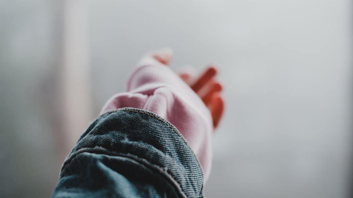 Close-up of a person reaching out with an arm in a denim jacket, evoking a sense of calm and connection.