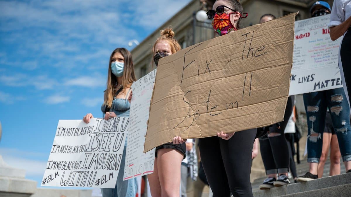 From below of unrecognizable protesters in face masks showing BLM placards on staircase in demonstration