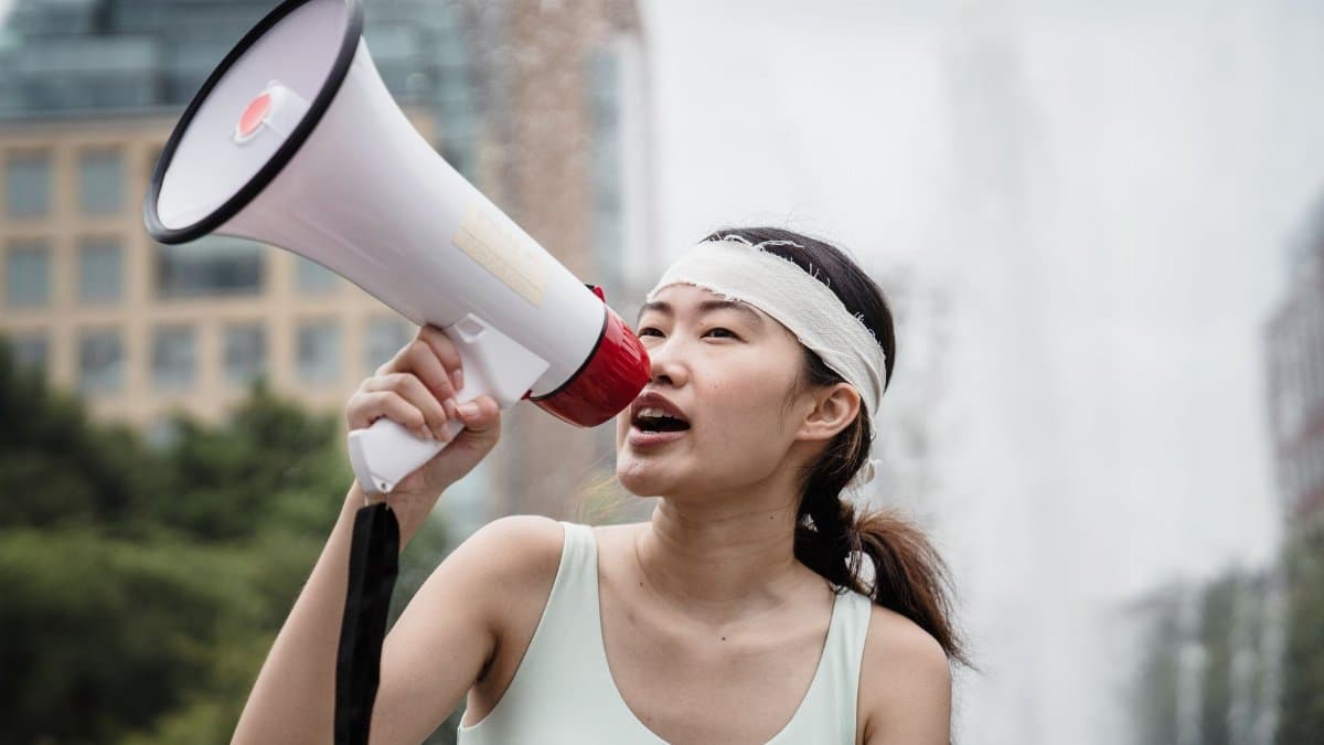 A woman passionately speaks into a megaphone during an outdoor protest, emphasizing activism and nonviolence.