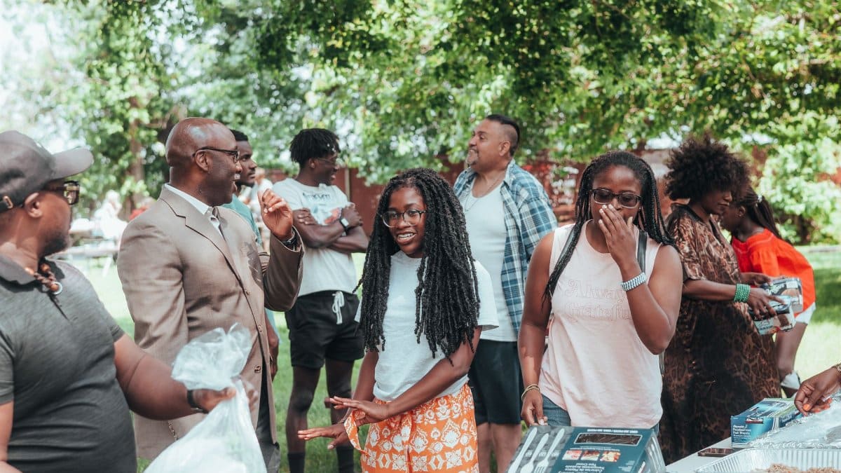 A diverse group of people engaging in conversation and laughter during an outdoor social event.
