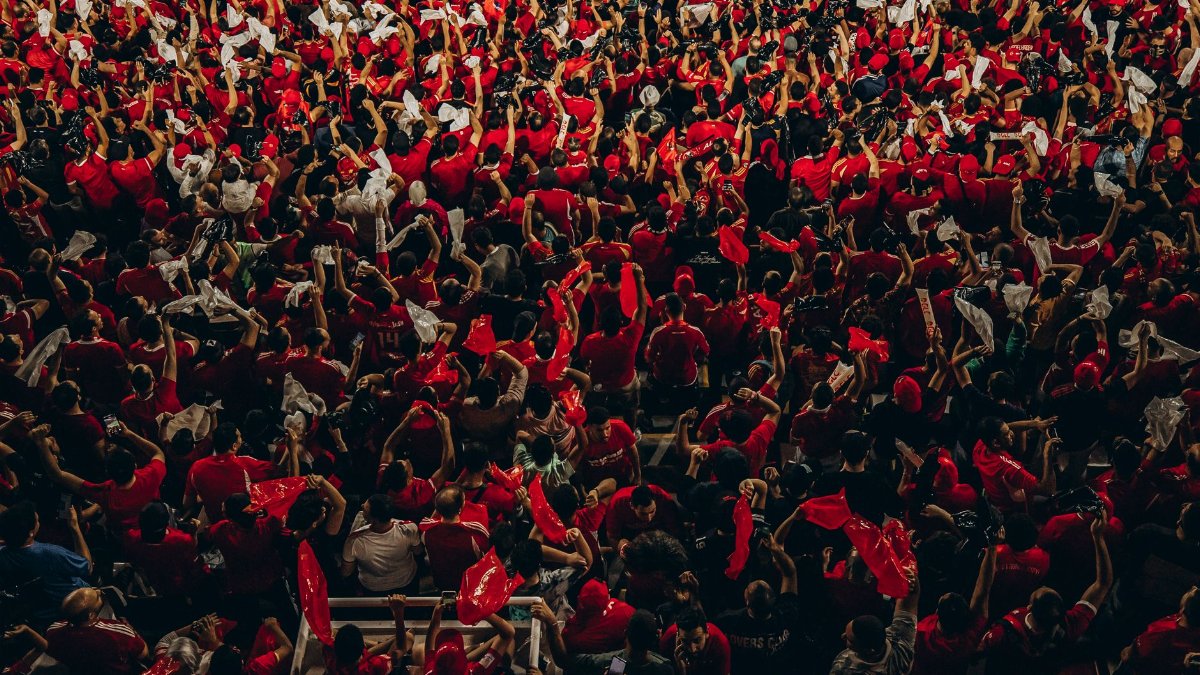 A large crowd of vibrant football fans cheering energetically during a match.