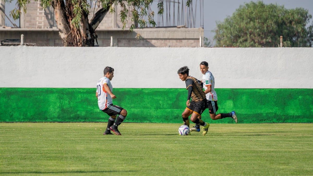 Competitive soccer game featuring young men in action on a sunny outdoor pitch.