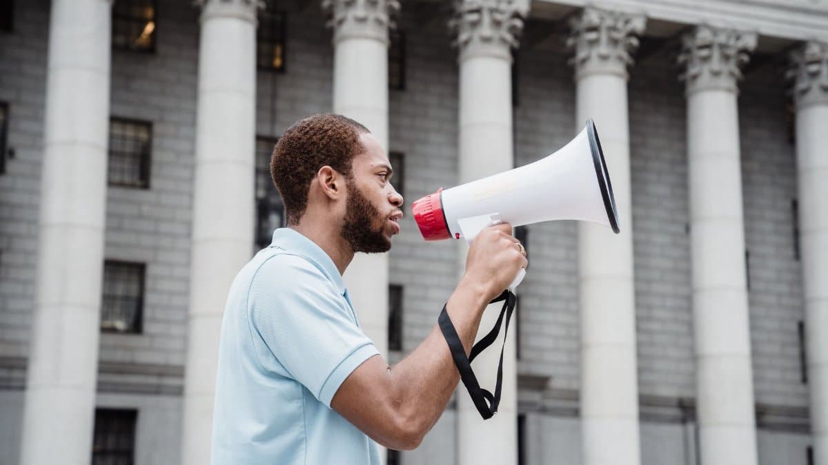 Person using a megaphone in a peaceful protest outside a court building.