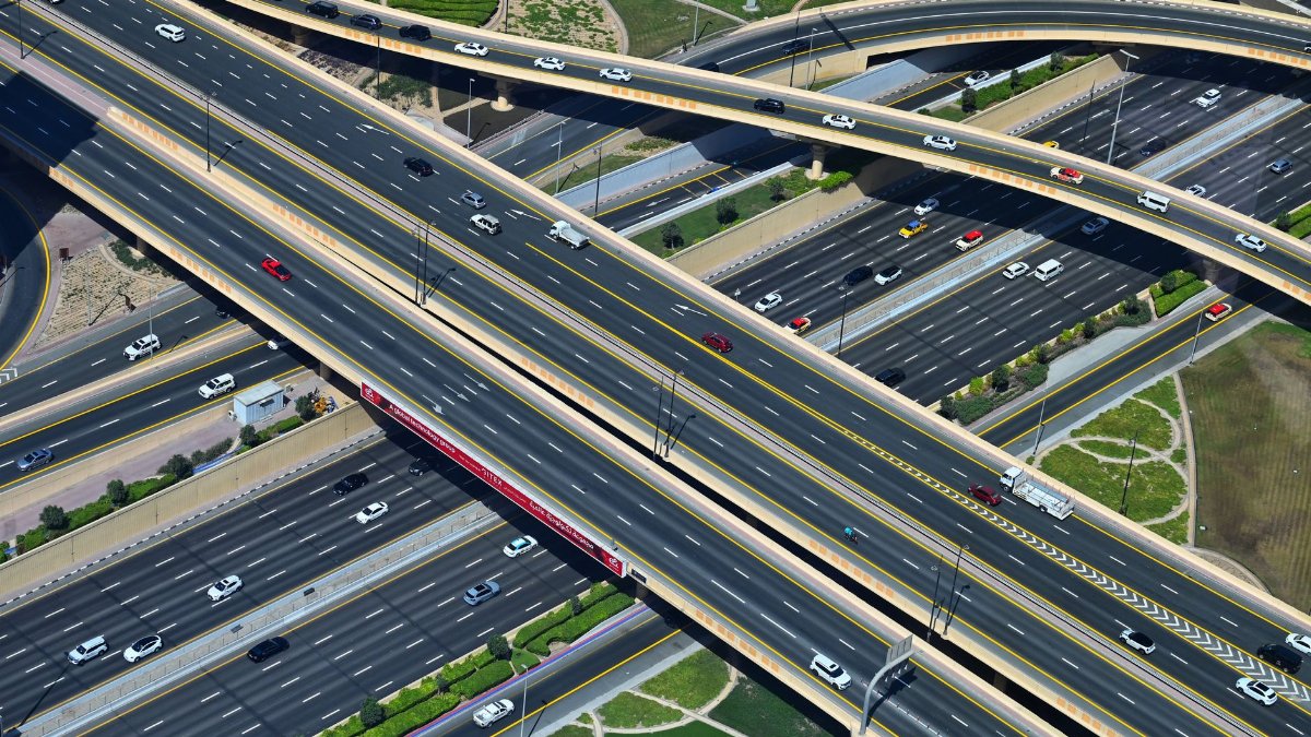 Aerial shot of a modern highway interchange with various vehicles and overpasses.
