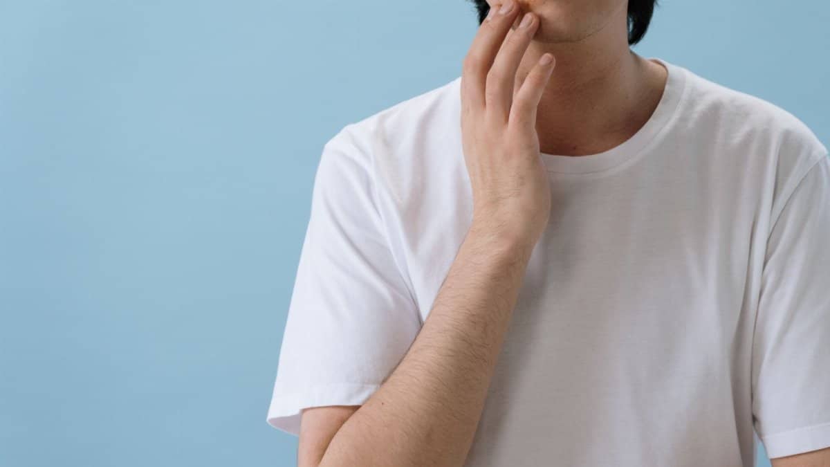 Close-up of a man touching his face showing signs of a skin condition or allergy.