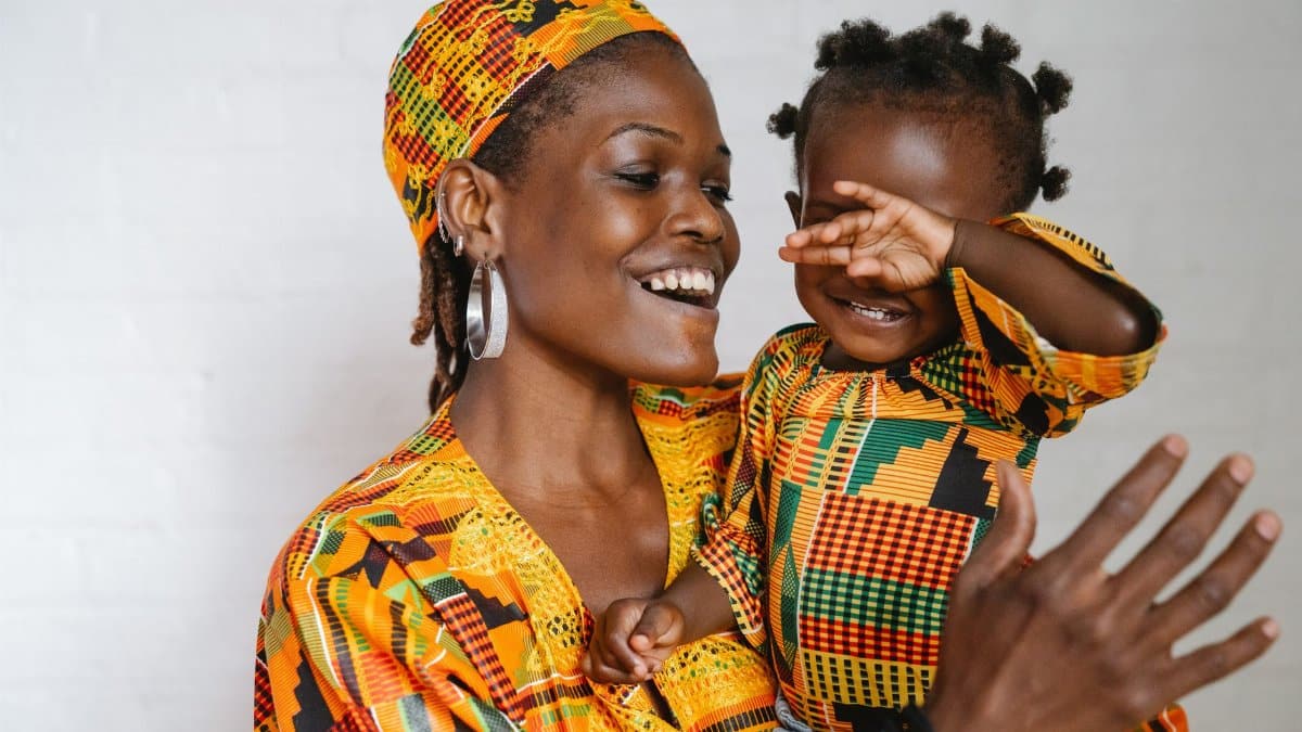 Joyful mother and daughter bonding in vibrant traditional clothes, expressing love.