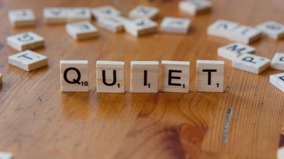 Scrabble tiles spelling 'QUIET' on a wooden surface, symbolizing calm and tranquility.