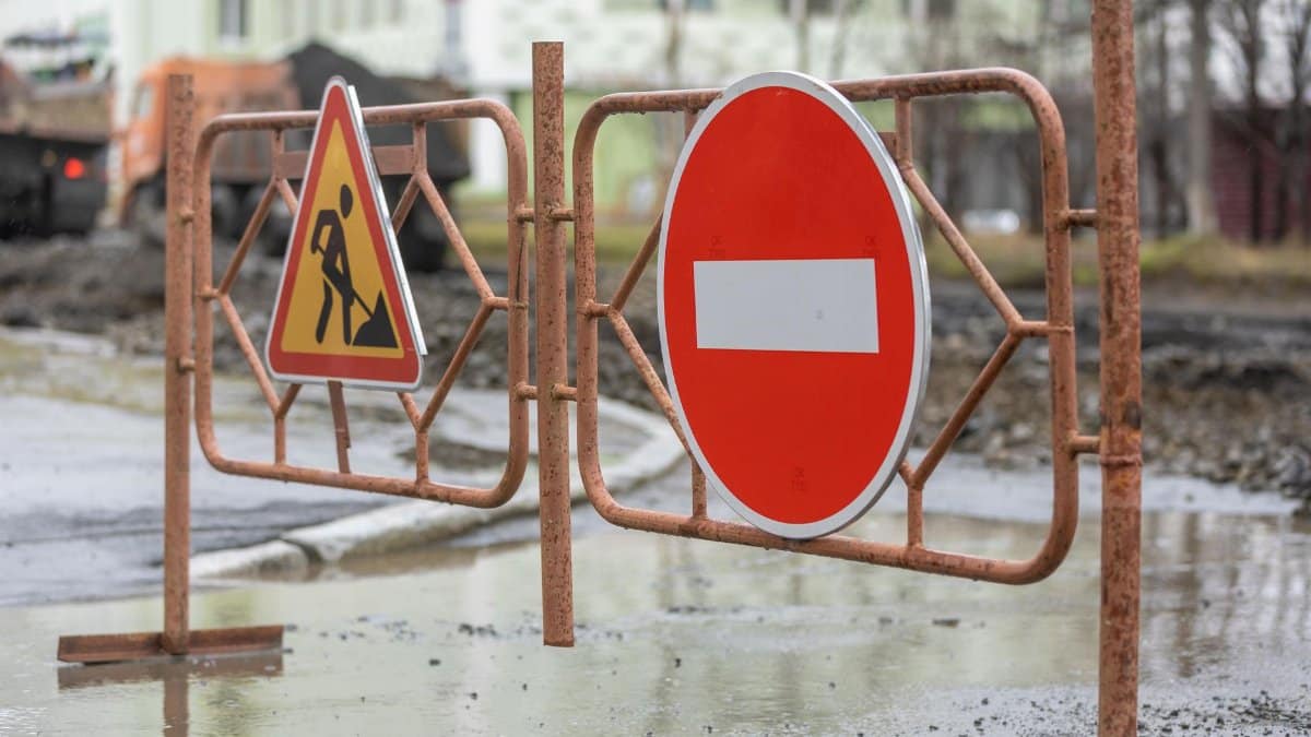 Close-up of road work and no entry signs at a construction site on a rainy day.