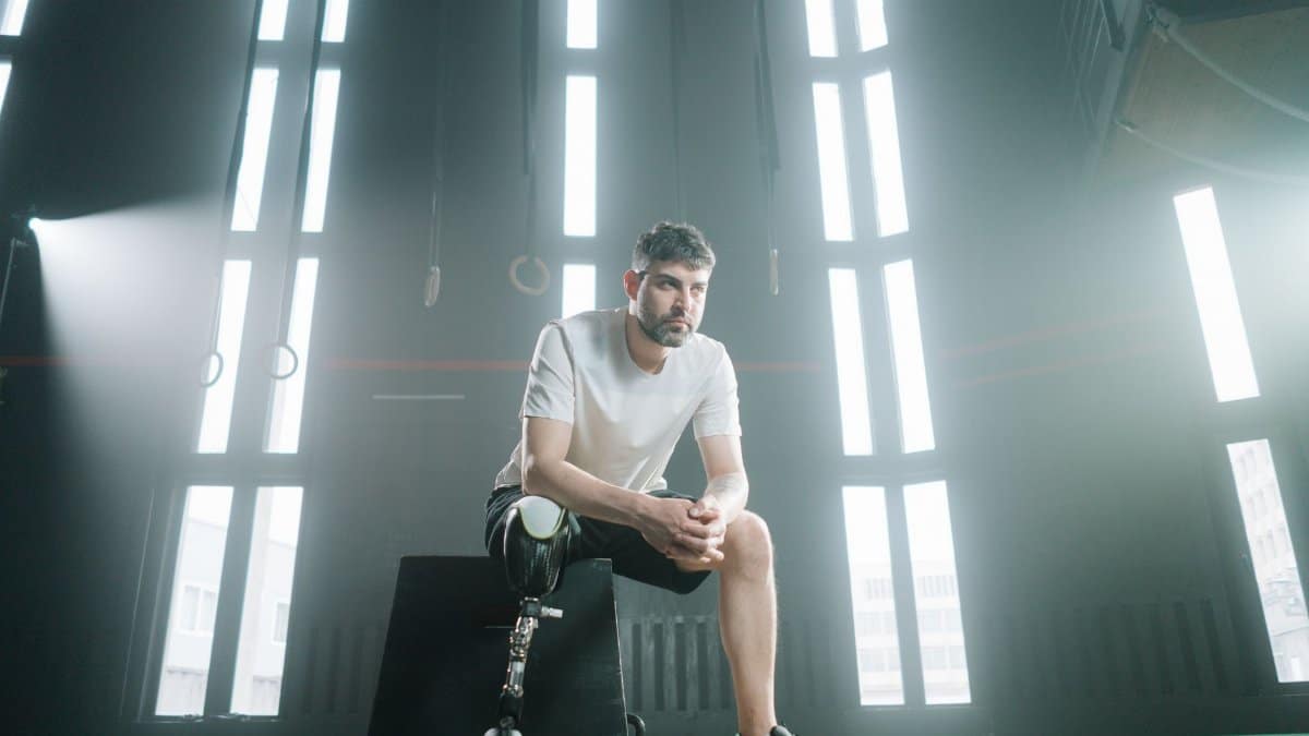 Male athlete with prosthetic leg sitting in a sunlit gym, embodying strength and determination.