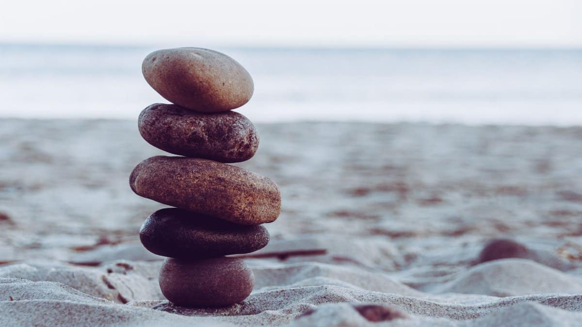 Peaceful scene of carefully balanced stacked stones on a sandy beach, evoking calmness and tranquility.