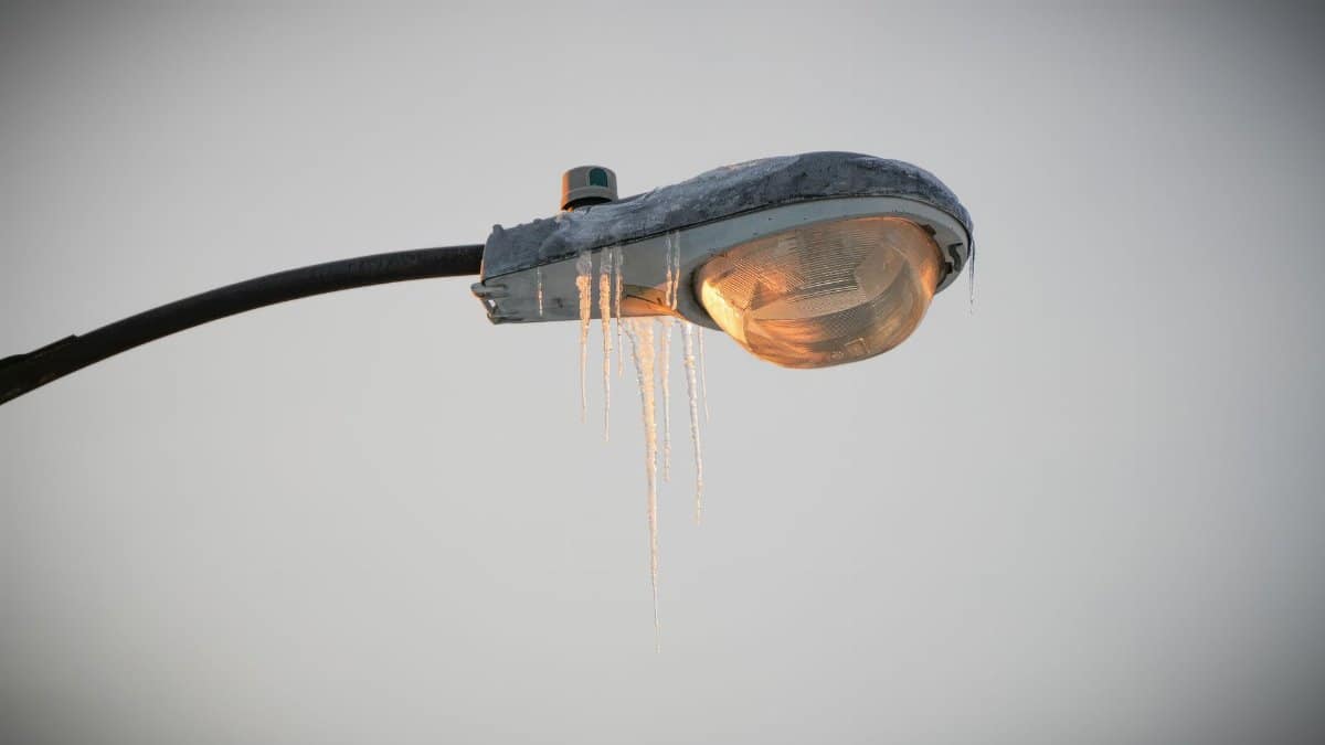 Frozen icicles hang from a street lamp during a cold winter day, captured in detail.