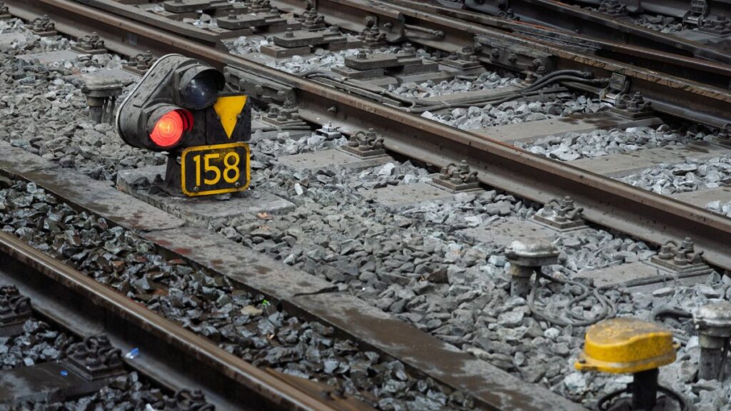 Detailed view of train tracks featuring a red signal light and numbered marker 158.
