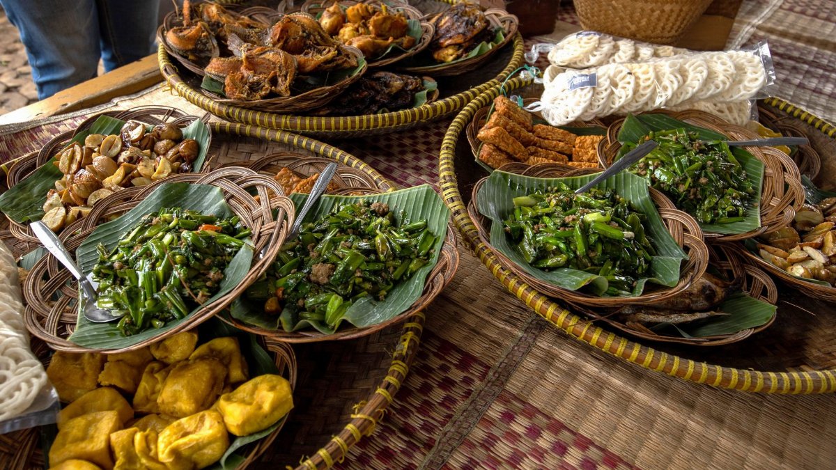 A vibrant spread of traditional Indonesian dishes featuring various local foods beautifully arranged on woven mats.