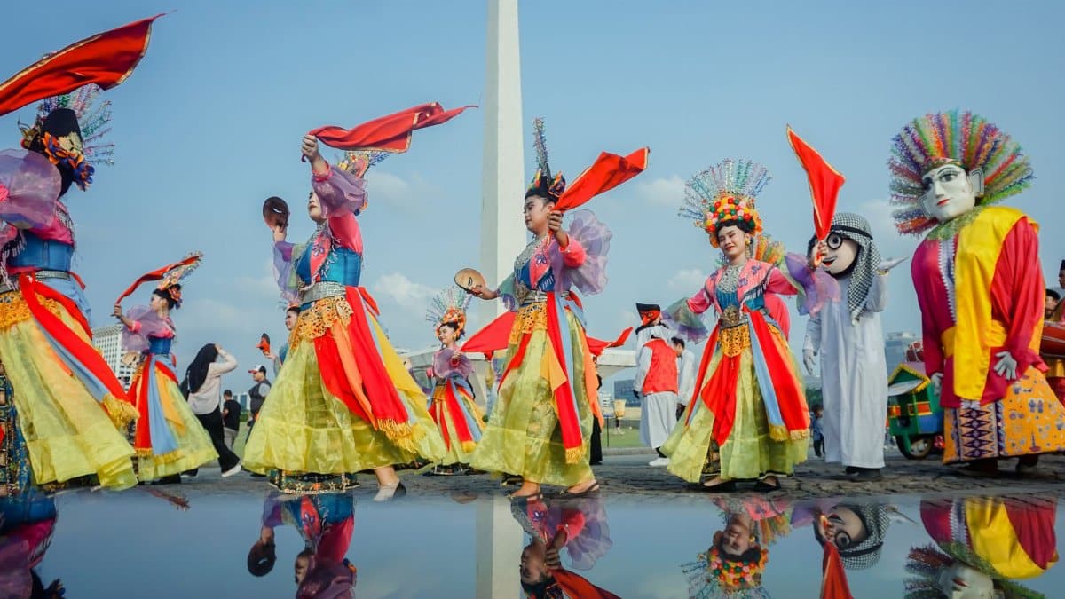 Vibrant carnival dancers perform at Monas, Central Jakarta, showcasing traditional costumes and cultural artistry.