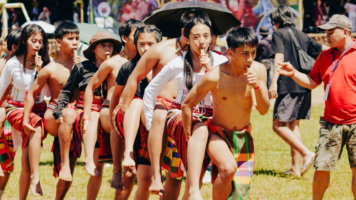 Group of people in traditional Filipino attire performing a cultural dance outdoors.
