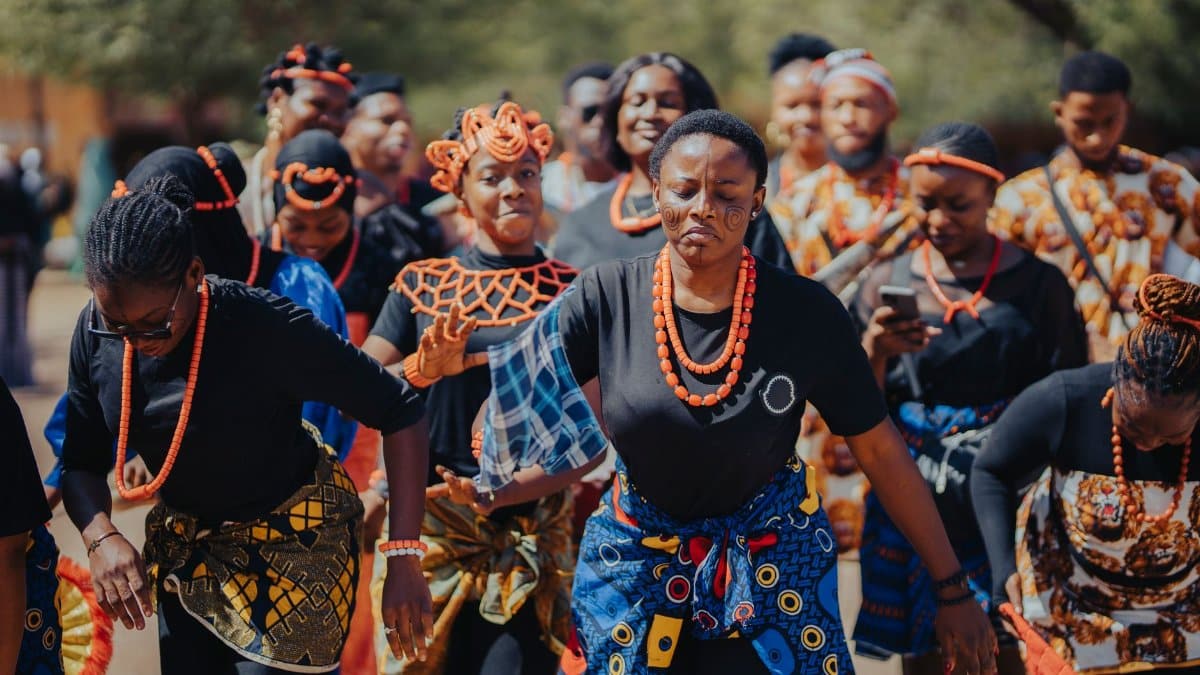 A group of people in traditional African attire performing a cultural dance outdoors.