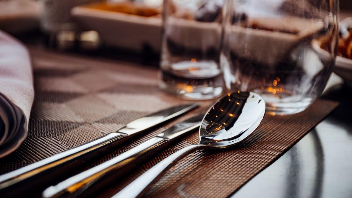 Close-up view of elegant cutlery on a dining table with a modern setting, featuring reflections in the silverware.