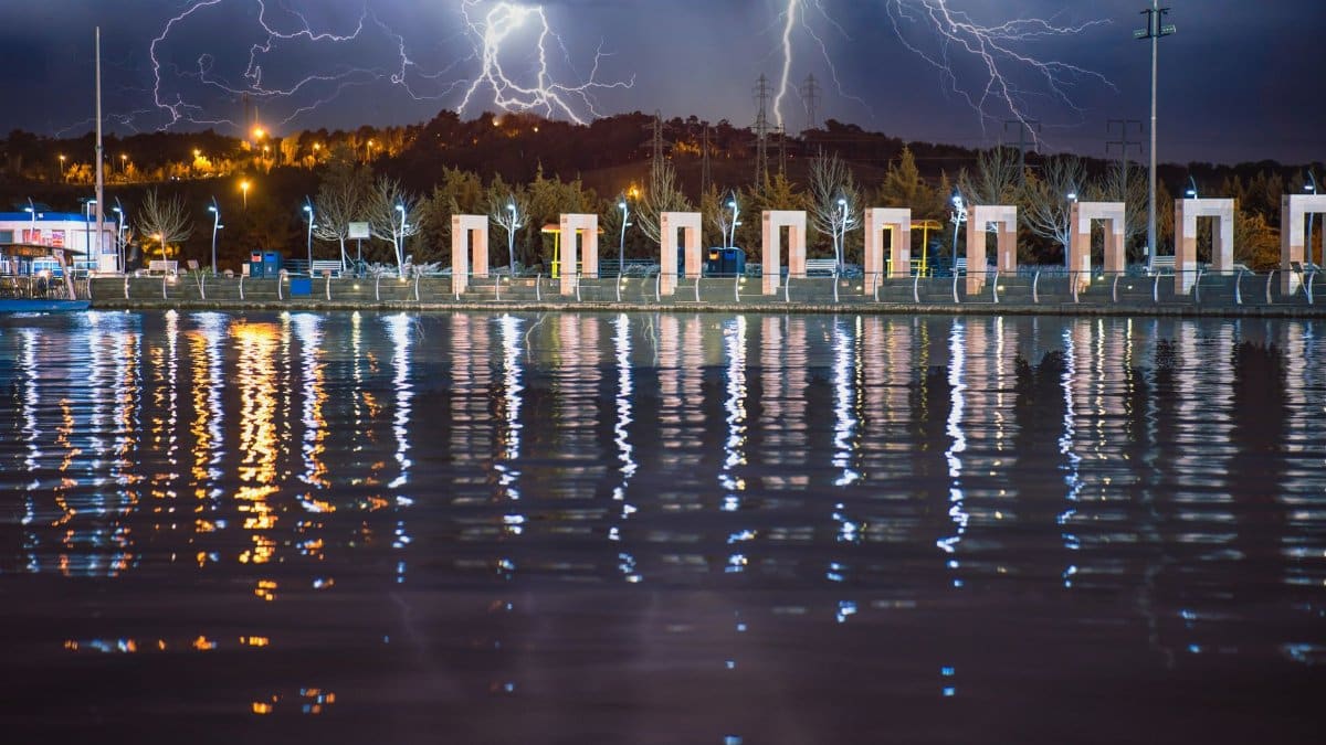 A vivid lightning storm illuminates the night sky above Tehran's waterfront, showcasing nature's power.