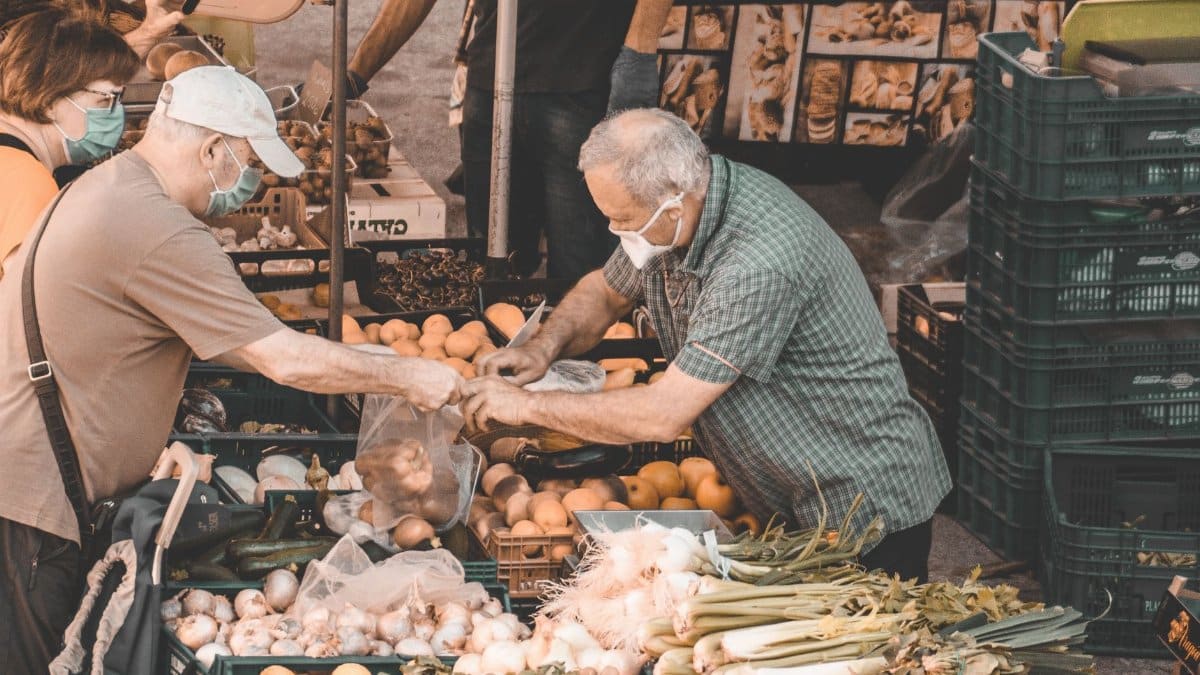 People shopping at a vibrant market in Barcelona, filled with fresh fruits and vegetables.