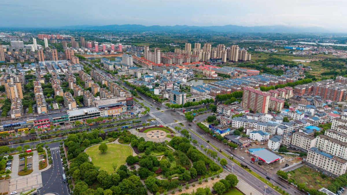Aerial view of Luoshan County's urban landscape with green parks and high-rise buildings.