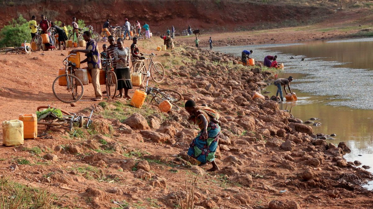 People gathering water by the riverside in Kigoma, showcasing daily life in Tanzania.