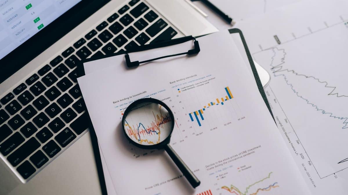 Overhead view of financial charts, laptop, and magnifying glass, ideal for business analysis themes.