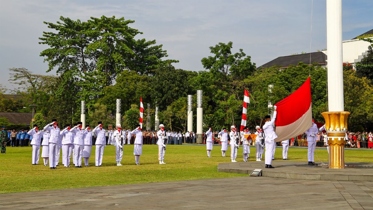 Formal flag raising ceremony at a public event in Jawa Barat, Indonesia. Uniformed officials in attendance.