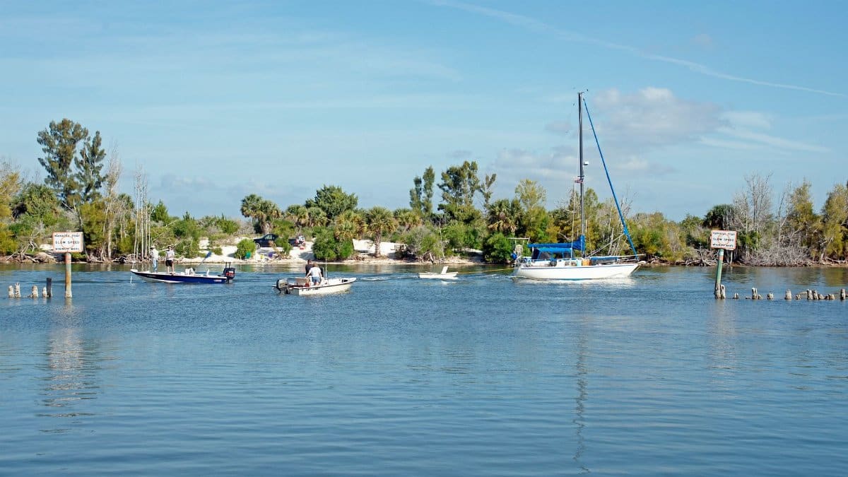 Boats sail on Haulover Canal under a clear blue sky in Mims, Florida.