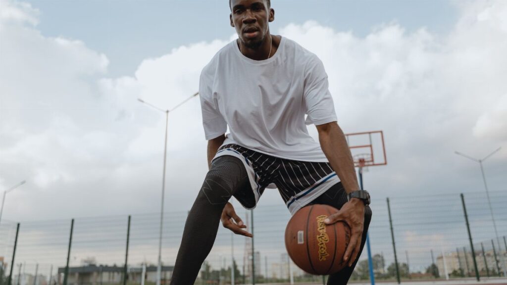 A focused athlete dribbles a basketball on an outdoor court, embodying fitness and agility.